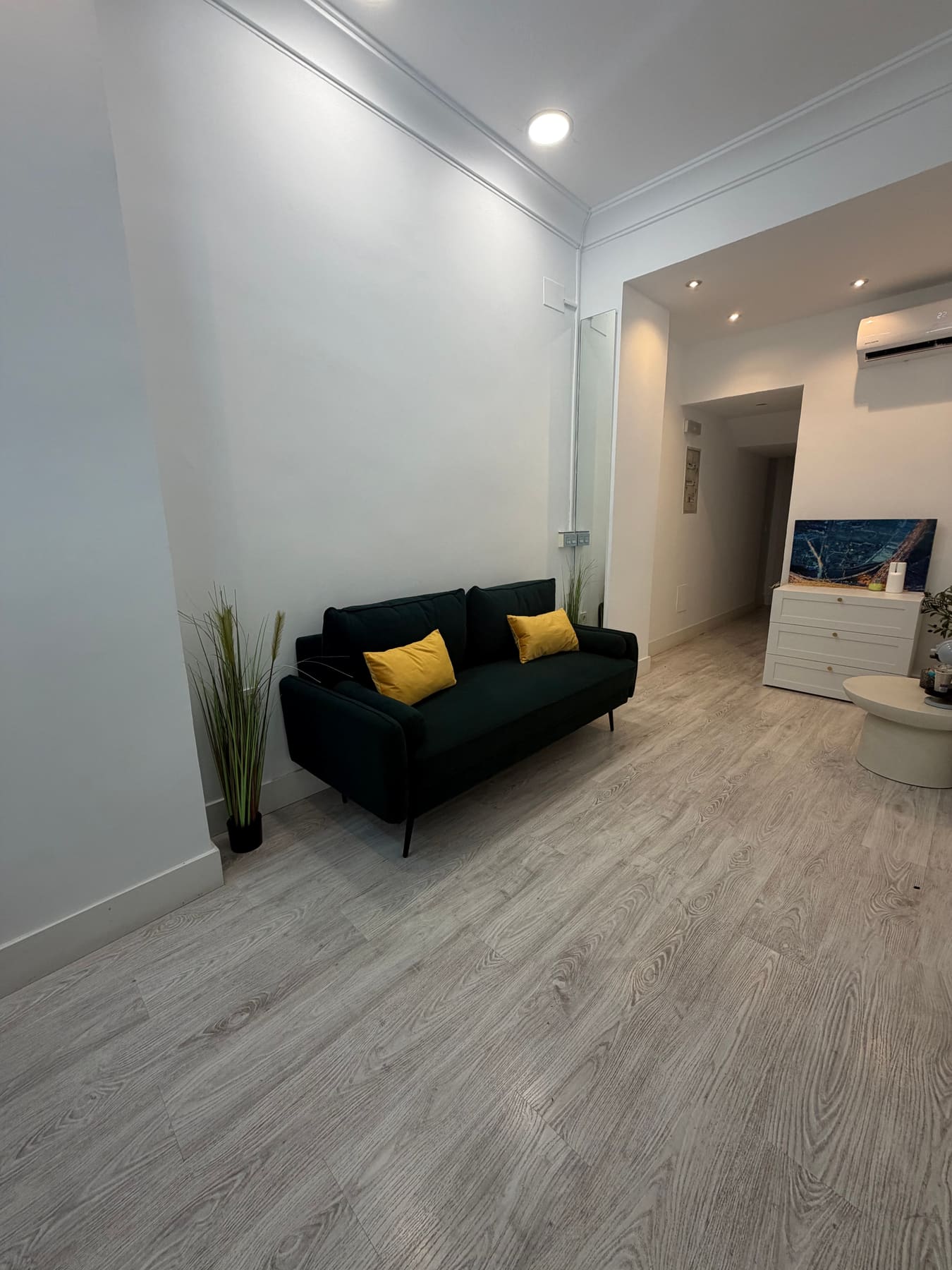 Seating corner of the Milla Homes office with a dark green sofa and yellow cushions